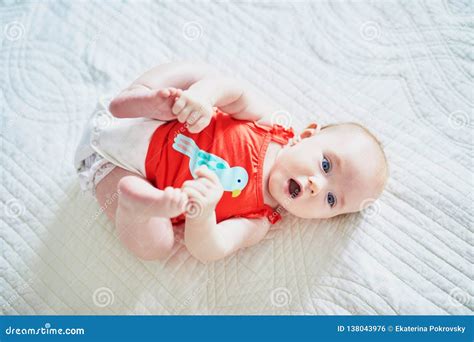 Cute Baby Girl Lying On Her Back And Touching Her Feet Stock Photo