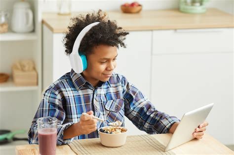 Niño Africano Con Pelo Rizado En Auriculares Comiendo Cereal Y Usando