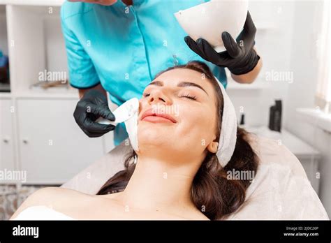 Facial Beauty Procedure Beautician In Latex Gloves Applying With Spatula Rejuvenation Mask On