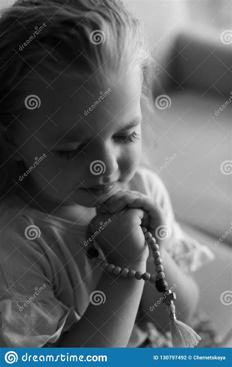 Cute Little Girl With Beads Praying Indoors Stock Photo