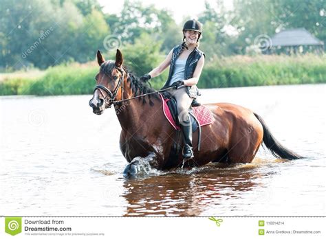 Smililng Young Teenage Girl Riding Horseback In River Stock Photo