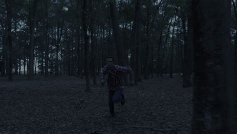 Man Frantically Running Away From Something In Dark Forest At Night