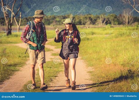 Two People Walking On Path In Meadow Field Male And Female Traveler