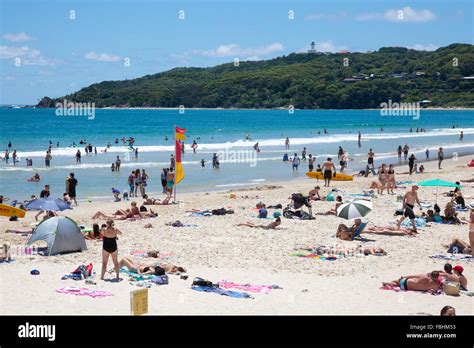 main beach at byron bay with sunbathers and cape byron lighthouse in the distance australia