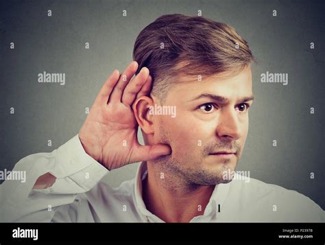 Young Man Holding Hand At Ear Concentrated On Eavesdropping Curious