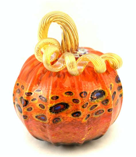 An Orange Glass Pumpkin With Gold Accents On Its Face And Handles
