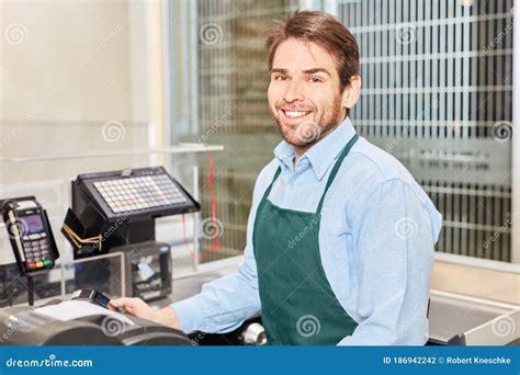 Friendly Cashier At The Cash Register In The Supermarket Stock Photo