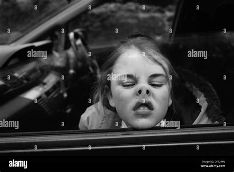 Girl Pressing Nose Against Car Window Whilst Winding It Up To Make