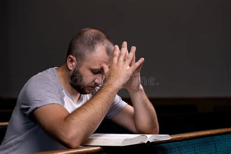 A Young Guy Sits On A Church Bench Reads The Bible And Prays The
