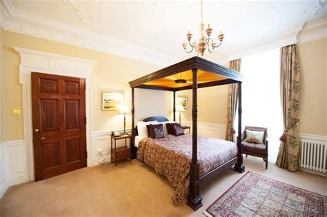 A Bed Room With A Neatly Made Bed And A Chandelier