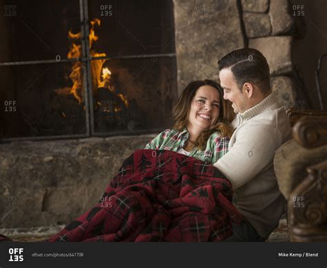 Smiling Caucasian Couple Cuddling On Floor Near Fireplace Stock Photo