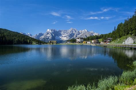 Landscape Photography Of Mountain Near Body Of Water Surrounded By Pine