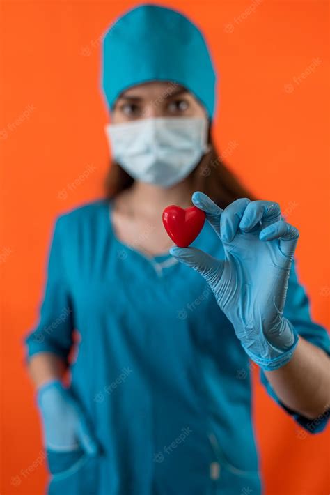 premium photo nurse in blue uniform with mask gloves holding small red heart in operating room