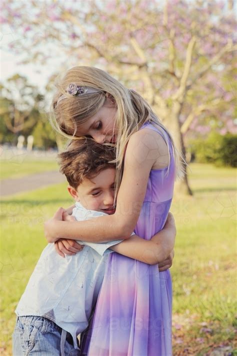 Image of Happy brother hugs big sister in the park - Austockphoto