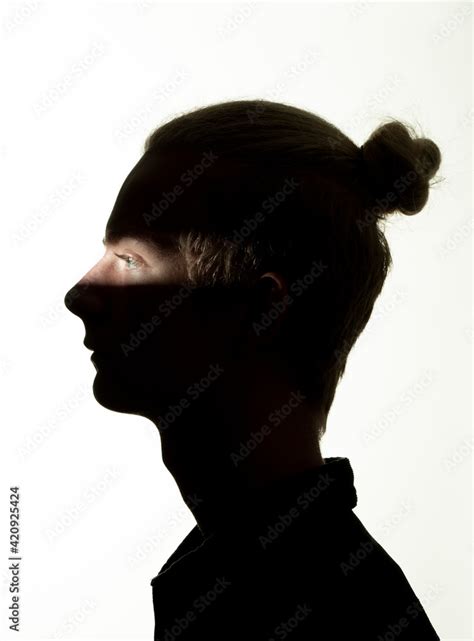 Head And Shoulders Portrait Of Teenage Boy Hidden In Shadow On White