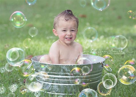 He is sat in a baby bath seat which is hidden from view by the soap suds. Bubble bath photo session