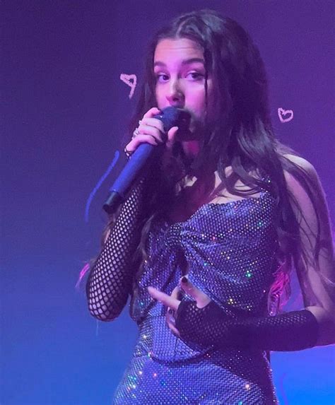 a woman with long hair wearing a silver dress and holding a microphone in her hand