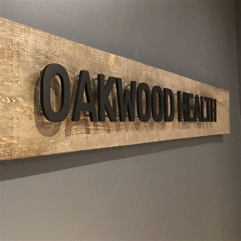 The Oakwood Health Sign Is Hanging On The Wall
