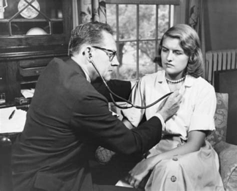 male doctor examining a female patient with a stethoscope poster print 24 x 36