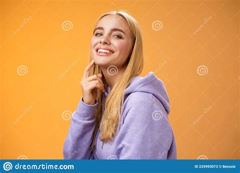 attractive sassy self assured caucasian blond female in purple hoodie turning camera touching
