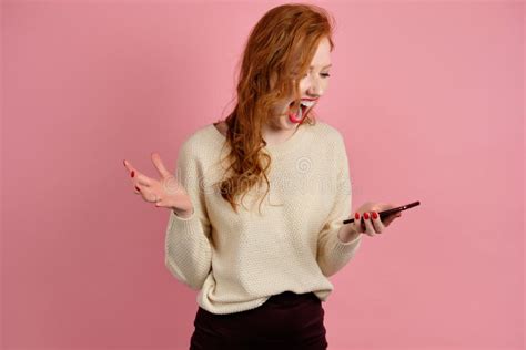 Beautiful Red Haired Girl With Red Lipstick Stands On A Pink Background