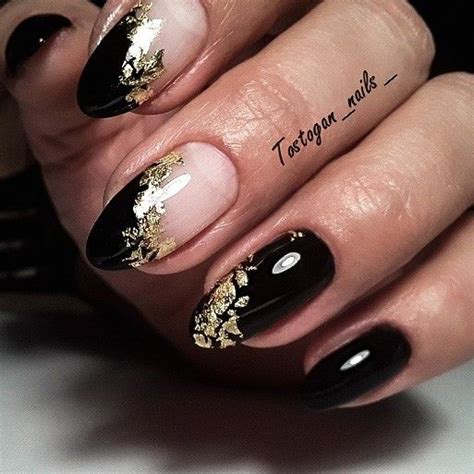 A Woman S Hand With Black And Gold Manies On Her Nails Which Are