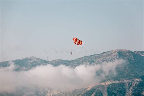 Red And White Parachute On A Clear Blue Sunny Day With Clouds Stock