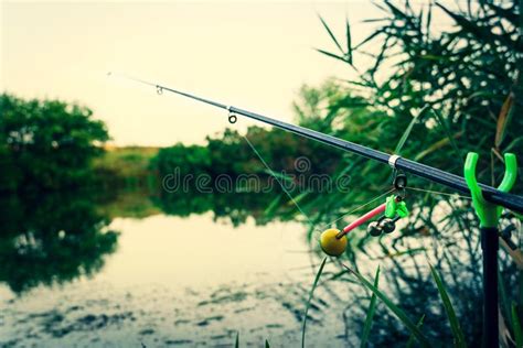 Fishing Rod On The River Bank Catching Fish At Sunrise Stock Image