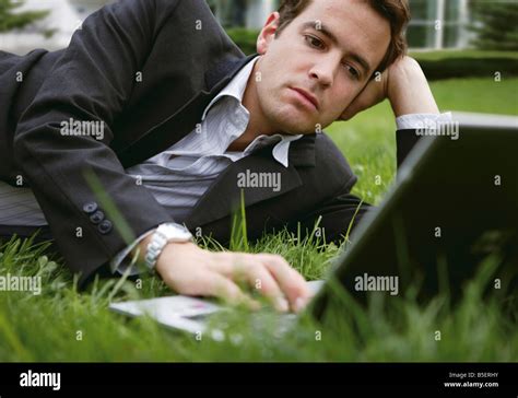 Businessman Lying On Grass While Using A Laptop Stock Photo Alamy