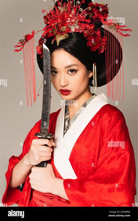 Brunette Japanese Woman Posing With Sword Isolated On Grey Stock Photo