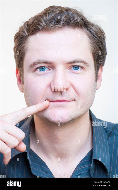 Portrait Of Young Caucasian Ethnicity Blue Eyed Man Points On His Lips