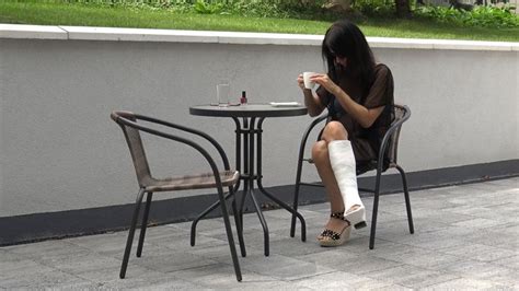 A Woman Sitting At A Table With An Injured Leg On The Ground Next To Her