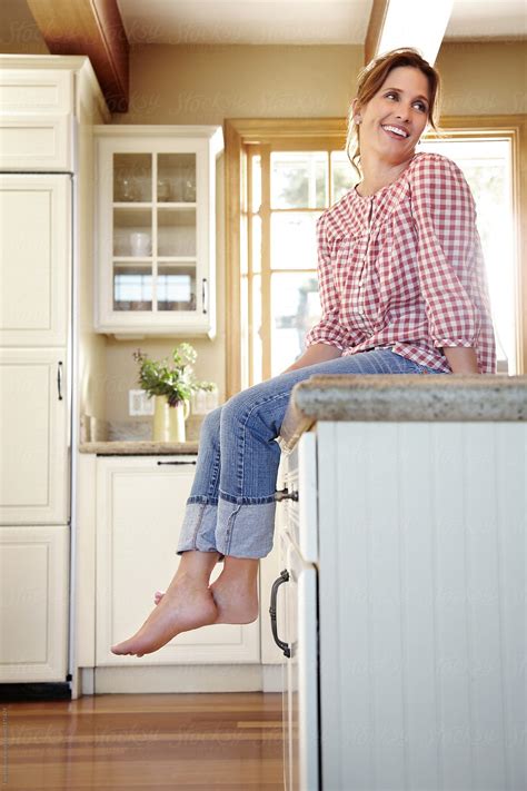 Portrait Of Woman In Her 30s Sitting On Counter In Kitchen At Home