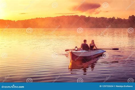 Couple In Love Ride In A Rowing Boat On The Lake During Sunset