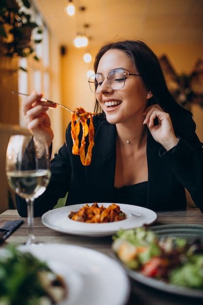 Jeune Femme Manger Pâtes Dans A Café Photo Gratuite