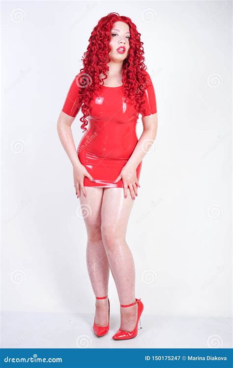 Hot Sexual Redheaded Girl With Plus Size Body Wears Fashion Latex Rubber Red Dress And Posing On