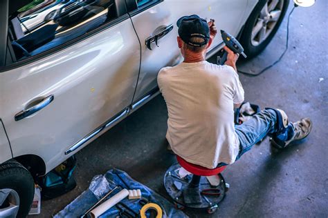 A Car Mechanic Working On An Old Car In A Workshop Car Restoration