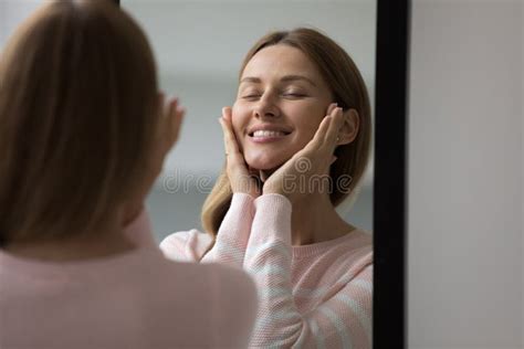 Attractive Young Woman Looks At Mirror Touches Her Perfect Face Stock