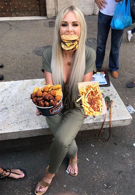 A Woman Sitting On A Bench Holding Two Plates Of Food In Front Of Her Face