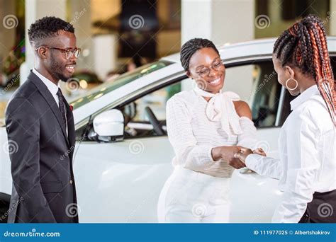 Customer Buying A Vehicle At Car Dealership Woman And Man Handshaking