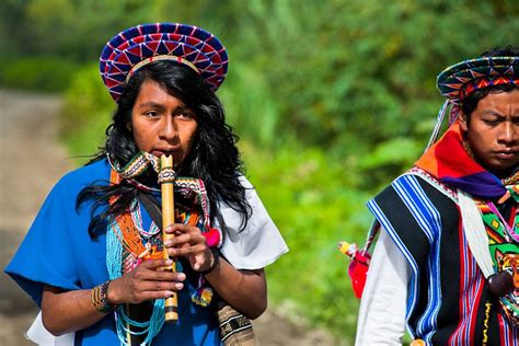 a native from the kamentsá tribe wearing a colorful headgear plays flute during the carnival