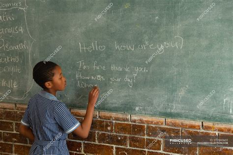 Schoolgirl Writing On Chalkboard In Classroom At School — Student