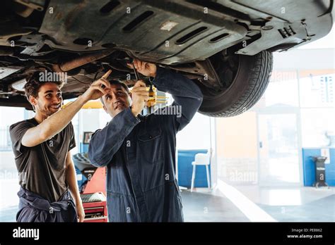 Mechanic Fixing The Car With Coworker Pointing And Smiling Two Auto