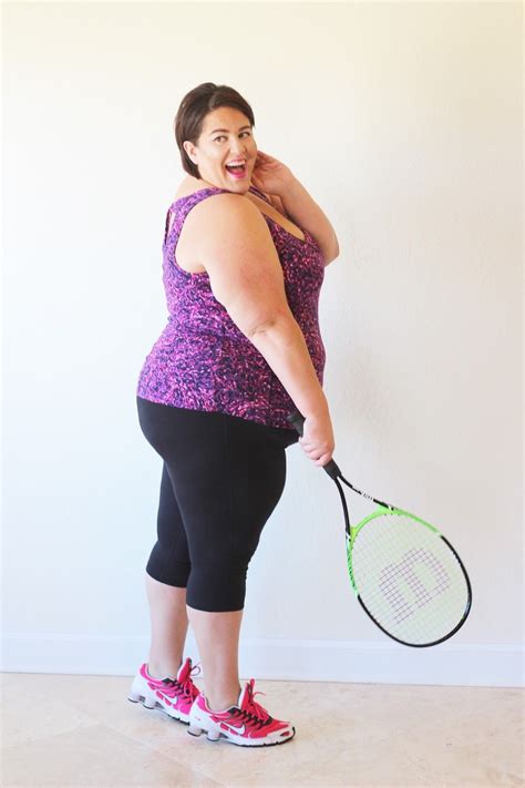 A Woman Holding A Tennis Racquet In Her Right Hand And Smiling At The