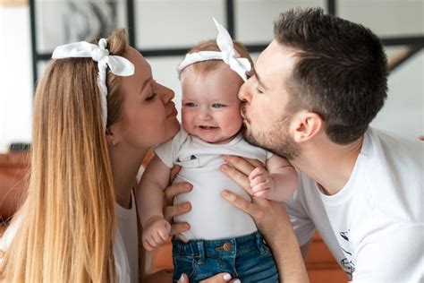 Mamá Y Papá Besando A Su Adorable Bebé Foto Premium
