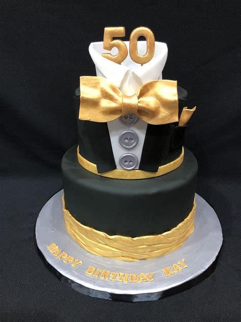 A 50th Birthday Cake With A Bow Tie And Button On The Top Is Decorated