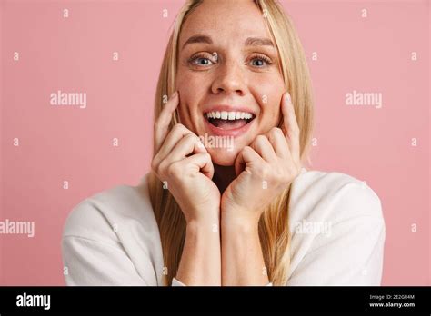 Cheerful Beautiful Girl Smiling And Pointing Fingers At Her Cheeks Isolated Over Pink Background
