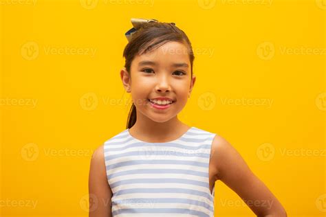 Beautiful Asian Girl Sitting On Yellow Background Happy Little Asian Girl Smiling 7717023