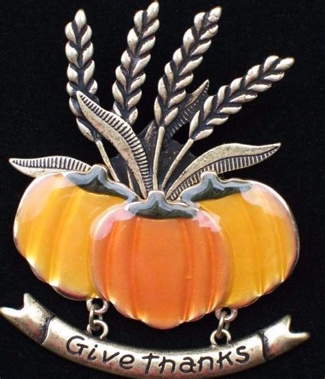 A Silver And Orange Pumpkin Brooch With The Words Give Thanks On Its Side