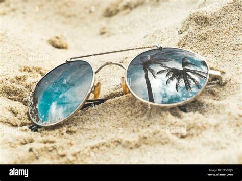 Mirrored Sunglasses Close Up On The Beach Sand With Palm Trees
